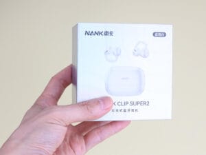 NANK Clip Super2 Frost White TWS earbuds rigid drawer packaging box held in hand, showing holographic specialty paper surface with iridescent light effects and spot UV coated product imagery